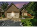 Charming brick home featuring a well-manicured lawn, and a two-car garage with barn-style doors at sunset at 3802 Abbott Ln # 14, Powder Springs, GA 30127