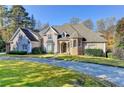 Stately two-story home with a circular driveway and lush landscaping on a sunny day at 3871 River Mansion Dr, Peachtree Corners, GA 30096
