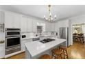 Bright kitchen featuring white cabinets, a marble countertop island with seating, and stainless steel appliances at 4250 Green Ridge Ne Dr, Marietta, GA 30062