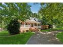 Attractive brick home featuring a full front porch, set among mature trees and green lawn at 4200 E 166 Hwy, Carrollton, GA 30116