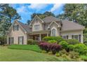 Elegant home showcasing lush landscaping, complemented by a covered front porch and traditional architectural details at 1605 Little Lisa Ln, Snellville, GA 30078