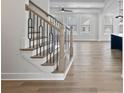 Modern staircase with light wood steps, contrasting black railing, and view to the living area at 4190 Hosch Reserve Dr, Buford, GA 30519