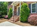 Close up of a brick front porch with manicured bushes, steps with metal railing, and an inviting entry way at 3559 Turtle Cove Se Ct, Marietta, GA 30067