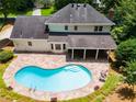Aerial view of a backyard featuring a kidney-shaped pool, stone patio, covered porch, and lush greenery at 3559 Turtle Cove Se Ct, Marietta, GA 30067