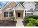 Inviting front entrance with a covered porch, complemented by landscaped flowerbeds and a brick facade with decorative windows at 3549 Daventry Nw Ln, Kennesaw, GA 30144