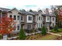 Brick townhomes with black fences, lush greenery, and colorful trees at 606 Goldsmith Ct # 114, Johns Creek, GA 30022