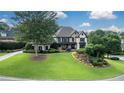 Attractive exterior showcasing meticulous landscaping around a two-story home with a stone facade and mature shade trees at 5995 Ettington Dr, Suwanee, GA 30024