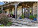 Inviting front porch with stone columns and facade, comfortable seating, and decorative plants flanking the entrance at 5995 Ettington Dr, Suwanee, GA 30024
