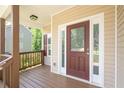 Inviting covered porch with a dark wood door, sidelights, and a stained wood deck and railing at 108 Spring View Br, Dallas, GA 30157