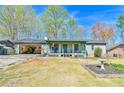 Charming single-story home with a covered front porch and open garage on a sunny day at 5774 Harbor Dr, Buford, GA 30518