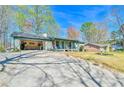 Single-story home with a covered front porch, open garage, and spacious driveway at 5774 Harbor Dr, Buford, GA 30518