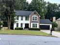 Charming two-story home boasts a combination of stone and white siding, complemented by a black garage door and manicured landscaping at 2798 Beddington Way, Suwanee, GA 30024