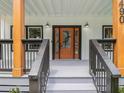 Close up of a decorative front door with sidelights and gray wood porch with wooden support beams at 490 Third Ave, Scottdale, GA 30079