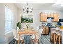 Cozy dining area features a modern light fixture, wood table with white chairs, and stainless steel appliances at 1362 Rogers Trce, Lithonia, GA 30058