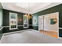 Elegant dining room with green walls, white trim, plush carpet, and a chandelier at 3072 Oaktree Ln, Duluth, GA 30096