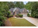 Beautiful single-Gathering home with lush landscaping, a circular driveway, and a classic brick facade at 8189 N Pine Cone N Dr, Villa Rica, GA 30180