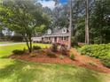 Landscaped front yard featuring a brick home, colorful plantings, and mature shade trees at 4023 Oak Crest Dr, Tucker, GA 30084