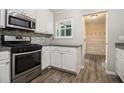 Modern kitchen with stainless steel appliances, white cabinets, and stylish backsplash, seamlessly connecting with hall at 1621 Northlake Springs Ct, Decatur, GA 30033