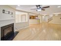 Open living room with a decorative fireplace, ceiling fan, and light wood flooring throughout at 7567 Waverly Loop, Fairburn, GA 30213
