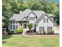 This home features a manicured lawn, mature trees, and combination stone and gray siding at 3860 Overlake Dr, Cumming, GA 30041