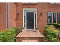 Inviting front entrance with a classic black door, brick steps, and decorative plants at 1015 Legacy Walk, Woodstock, GA 30189