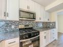 Bright kitchen featuring white cabinetry, stainless steel appliances, and mosaic tile backsplash at 2391 Cove Rd, Lithonia, GA 30058