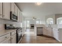 Open-concept kitchen with stainless steel appliances, white cabinetry, and hardwood floors, seamlessly flowing into the living area at 70 Trinity Lane, Covington, GA 30016