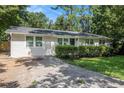 View of a single-story home with a concrete driveway surrounded by mature trees at 1975 Glenmar Dr, Decatur, GA 30032