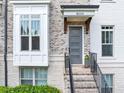 Close up on the townhome featuring gray brick, a bay window, and a welcoming gray front door at 4311 Parkside Pl, Atlanta, GA 30342