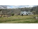 Traditional single-Gathering home with lush green yard and mature trees against a wooded backdrop at 4055 Haralson Mill Ne Rd, Conyers, GA 30012