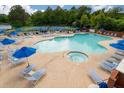 Community pool area with a hot tub, tennis courts, umbrellas, and lounge chairs at 860 N Bethany N Rd, Mcdonough, GA 30252