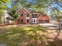 Two-story brick home featuring a manicured lawn, two-car garage, and mature trees in a desirable neighborhood at 819 Bermuda Run, Woodstock, GA 30189