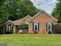 Brick ranch house with a landscaped lawn and mature trees at 175 Abner Dr, Mcdonough, GA 30252