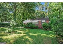 Charming brick home with a well-maintained lawn and mature trees in a serene, wooded setting at 2576 Godfrey Nw Dr, Atlanta, GA 30318