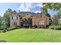 Brick two-story house with a landscaped lawn and mature trees at 2118 Town Manor Ct, Dacula, GA 30019