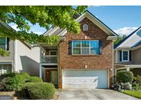 Brick townhouse with two-story elevation, attached garage, and landscaping at 695 Shadow Lake Dr, Lithonia, GA 30058