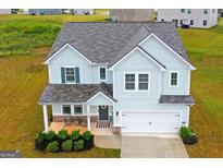 Two-story light blue house with a two-car garage and landscaping at 1168 Bodega Loop, Locust Grove, GA 30248