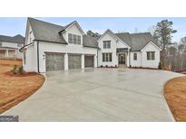 White farmhouse exterior with three-car garage and large driveway at 150 Dockside Dr # 382, Fayetteville, GA 30215