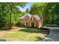 Brick house with a two-car garage and large front yard, surrounded by lush greenery at 2215 Whispering Pines Ln, Mcdonough, GA 30253