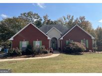 Brick house with green shutters, landscaping, and a walkway at 147 Wynnfield Blvd, Mcdonough, GA 30252