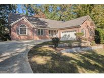 Brick ranch house with attached two-car garage and landscaped yard at 1241 Lambeth Se Way, Conyers, GA 30013