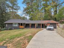 Charming single-story home with a long driveway, car and lush landscaping at 1973 Glendale Dr, Decatur, GA 30032