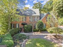 Stunning brick home featuring a lush landscaped front yard and a classic design at 7300 Chattahoochee Bluff Dr, Sandy Springs, GA 30350