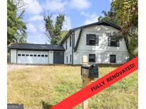 Renovated two-story home featuring an attached garage and classic architectural details with a well manicured lawn at 4239 Newcomb Rd, Decatur, GA 30034