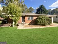 Charming red brick home with a well-manicured lawn and mature trees at 828 Pinevalley Dr, Forest Park, GA 30297