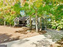 Charming gray home featuring a well-manicured front yard, natural landscaping, and a long driveway at 7193 Tara Dr, Villa Rica, GA 30180