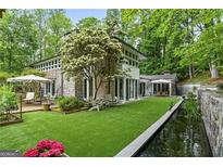 An exterior shot of a home with a large backyard including a koi pond, small deck, and chairs for lounging at 3033 E Pine Valley Rd, Atlanta, GA 30305