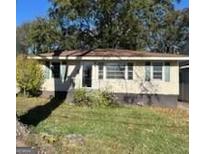 Modest single story home showing large front yard with mature trees and the need for some care at 1511 Walker Ave, College Park, GA 30337