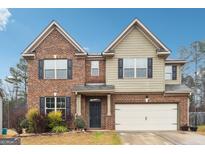Charming two-story home featuring a brick and siding exterior with an attached two-car garage at 1406 Stone Ridge Ct, Hampton, GA 30228