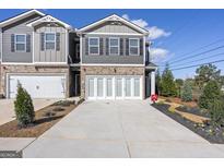 New two-story townhome with brick and gray siding, well maintained landscaping and a two car garage at 11567 Kimberly Way # 25, Hampton, GA 30228